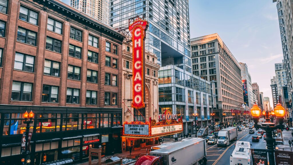 city landscape with the chicago theatre in the center. cars driving by at dusk
